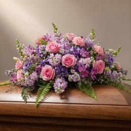 Pink and purple floral arrangement on a wooden casket