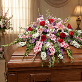 Casket spray with red roses, pink lilies, and purple accents