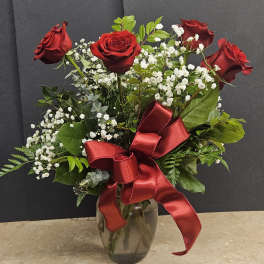 Red roses with baby's breath in a glass vase and red ribbon