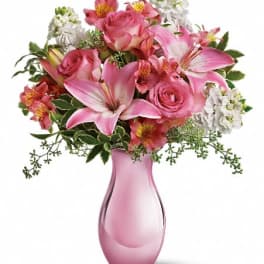 Pink roses and lilies arranged in a pink glass vase