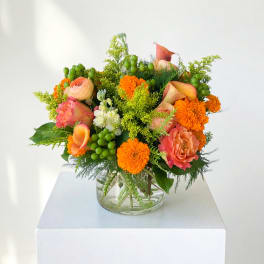 Colorful bouquet in a clear glass vase with orange, pink, and white blooms