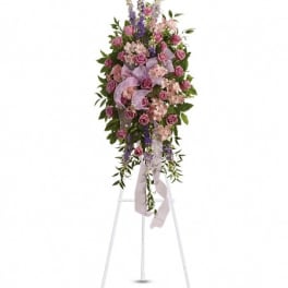 Standing floral spray with pink and purple flowers on a white easel