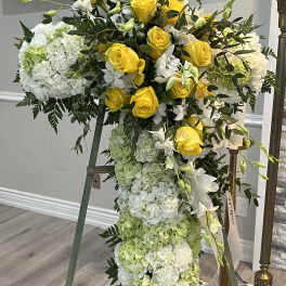 Tall standing floral cross with yellow roses and white hydrangeas