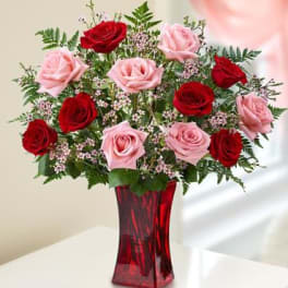 Red and pink roses arranged in a red glass vase