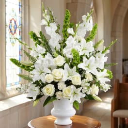 White floral arrangement in a white vase with green accents