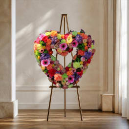 Heart-shaped floral wreath on a standing easel with bright mixed blooms