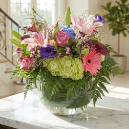 Mixed bouquet with lilies, roses, hydrangea, and a gerbera daisy in a glass vase