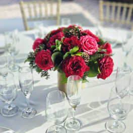 Red rose centerpiece in a gold vase on a set dining table