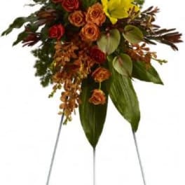 Standing floral spray with red roses and yellow lilies on a metal easel