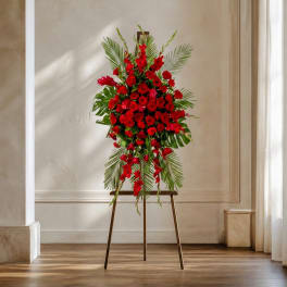 Tall red floral standing spray on an easel with palm leaves