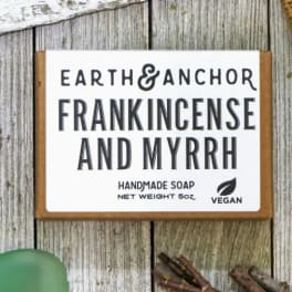 Frankincense and myrrh handmade soap bar on rustic wood with herbal accents