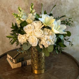 White roses and lilies arranged in a gold vase