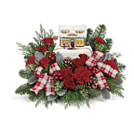 Christmas floral arrangement with red roses and plaid ribbons around a house ornament