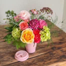 Mixed bouquet of roses and hydrangeas in a pink cup-style vase
