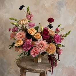 Mixed pink and peach floral arrangement in a gold vase
