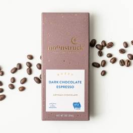 Box of dark chocolate espresso with coffee beans scattered around it