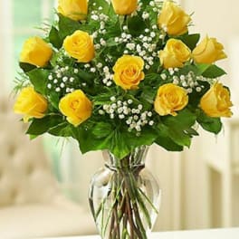 Yellow roses in a clear glass vase with white filler flowers
