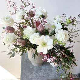 White and blush floral arrangement in a beige vase