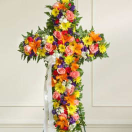 Cross-shaped floral spray with mixed bright flowers on a stand
