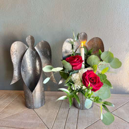 Red roses and white flowers arranged with a candle in a metal angel holder
