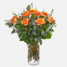 Bouquet of orange and yellow roses in a clear glass vase