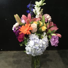 Mixed bouquet in a glass vase with lilies, roses, hydrangea, and snapdragons