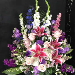 Large floral arrangement with pink lilies, roses, and purple flowers