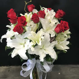 Bouquet of red roses and white lilies in a glass vase with a white ribbon