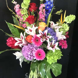 Colorful mixed bouquet in a glass vase with roses, lilies, and gerberas