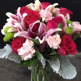 Bouquet of pink roses, calla lilies, and carnations in a glass vase