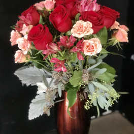 Bouquet of red roses and pink carnations in a tall vase