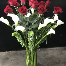 Red roses and white calla lilies in a clear glass vase