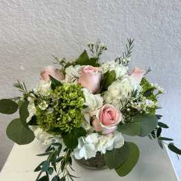 Pink roses and white hydrangeas arranged in a low glass bowl