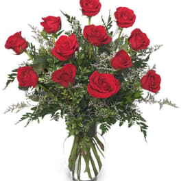 Arrangement of red roses in a clear glass vase with delicate white filler flowers