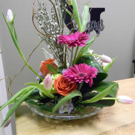 Mixed bouquet with pink gerberas, orange roses, and white tulips in a glass bowl