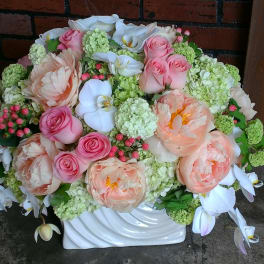 Large pastel floral arrangement in a white vase with pink and white blooms