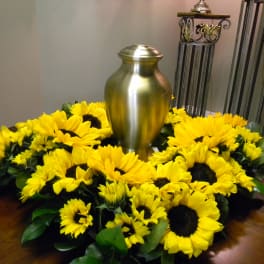 Sunflower wreath around a gold urn on a table