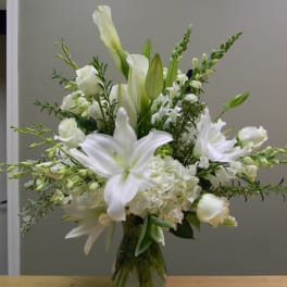 White lilies and roses arranged in a clear glass vase