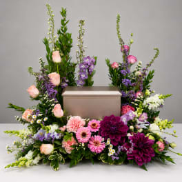 Floral arrangement surrounding a silver urn with pink, purple, and white blooms