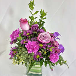Pink and purple bouquet in a clear square vase
