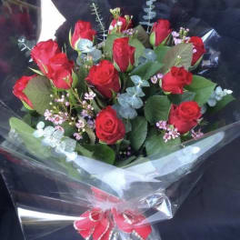 Bouquet of red roses wrapped in clear plastic with a red ribbon