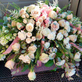Large arrangement of pale pink and white roses with ribbon accents