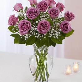 Arrangement of lavender roses with white baby's breath in a clear glass vase
