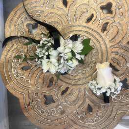 White floral corsage with black ribbon and matching white rose boutonniere on carved wooden table