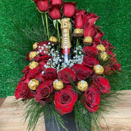 Red roses arranged around a champagne bottle with chocolates