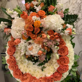 Large circular floral wreath with orange and white flowers on an easel
