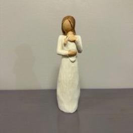 Small figurine of a girl in a white dress holding a teddy bear