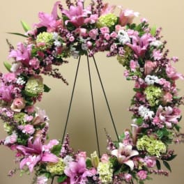 Pink and white floral wreath on a black stand