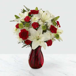 Red and white flower arrangement in a red glass vase