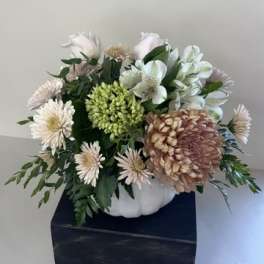 White and pale pink flowers arranged in a white pumpkin-shaped container